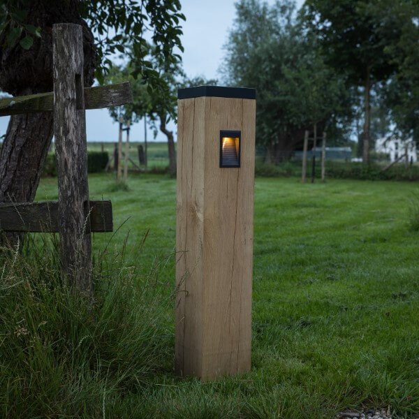 Solarbetriebene Wegbeleuchtung aus Holz mit schwarzer Halterung im Gras